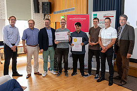 Die Gewinner des GFOS-Innovationsawards 2019: Robin Sauerborn (4. v. l.), Mert Özkaradeniz (4. v. r.) und Henry Herröder (3. V. re.) des Heinz-Nixdorf-Berufskollegs, unterstützt durch ihren Lehrer Dr. Michael Schmidt (2. v. r.), überzeugten die Jury rund um Burkhard Röhrig (2. v. l.) , Prof. Dr. Stefan Heinemann (3. v. l.) und Ralf Daumeter (re.) auf ganzer Linie. Christoph Hohoff (li.) führte durch die Veranstaltung. (Foto: FOM/Tim Stender)